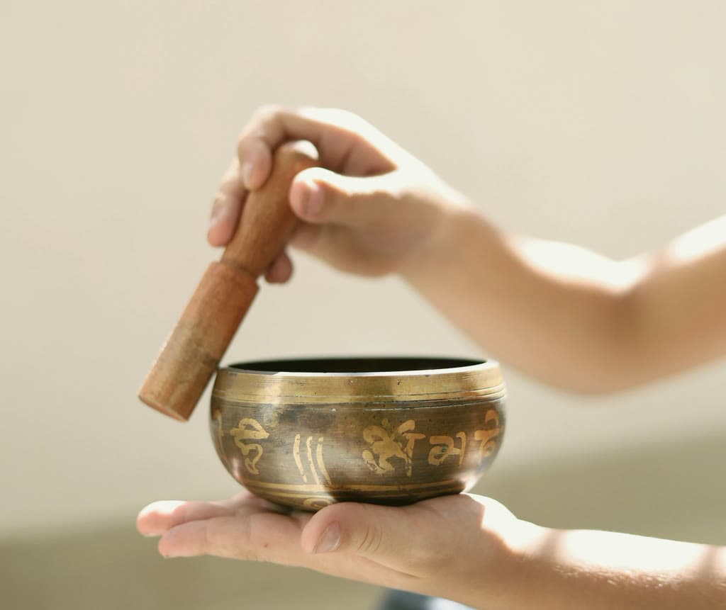 A hand striking a singing bowl